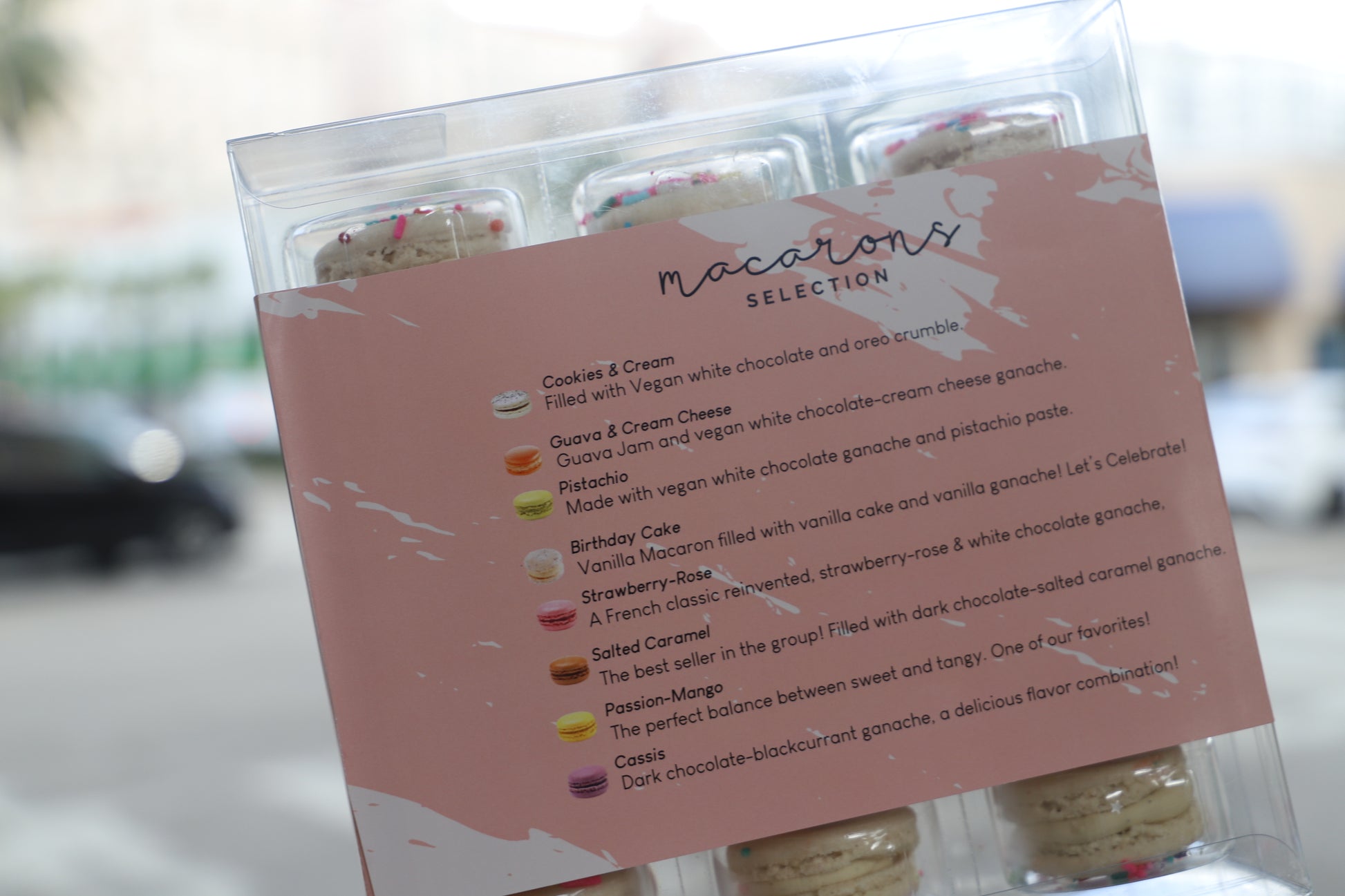 Flavor menu showcasing L’Artisane’s vegan macarons, including gluten-free options like salted caramel, pistachio, and strawberry-rose.